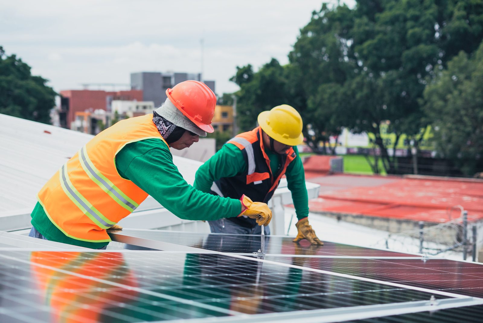 Due tecnici avvitano un modulo fotovoltaico sulla copertura di un edificio